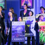women performers holding Playbelle board